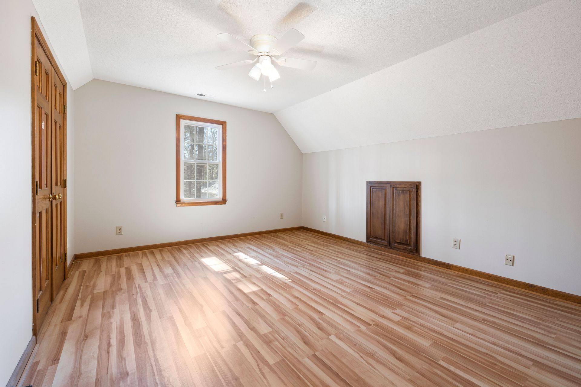 Bright empty room with hardwood floor and ceiling fan, perfect for real estate listings.
